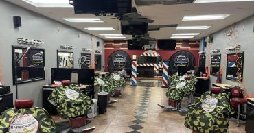 Interior of a modern barbershop with camo-covered chairs and multiple mirrors.