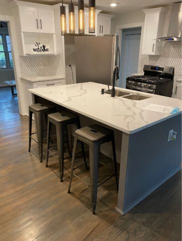 Modern kitchen with a marble island and metal stools.