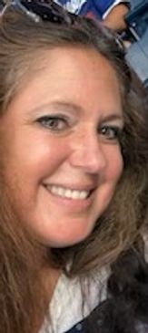 Smiling woman with long hair and sunglasses on her head.