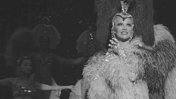 A glamorous showgirl in an elaborate blue feather costume.