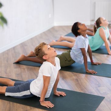 Kids doing yoga on mats indoors.