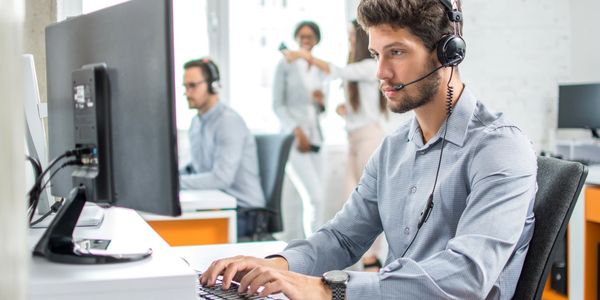 Young handsome male customer support phone operator with headset working in call center.