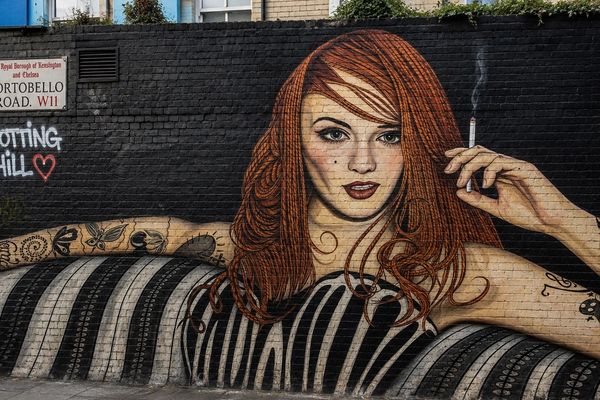 Street art of a red-haired woman on a brick wall.