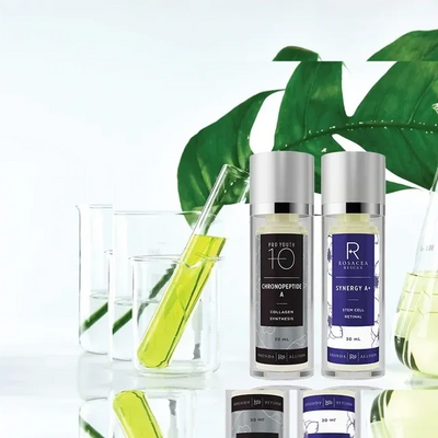 Two skincare serums with lab glassware and green leaves in the background.