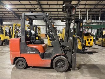 A red Nissan forklift parked indoors in a warehouse.