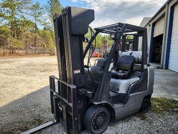 A forklift parked outside near a warehouse.
