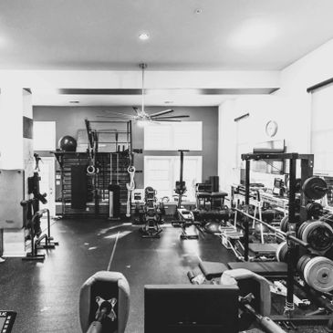 Home gym with weight rack, rower, exercise bike, and fitness equipment.