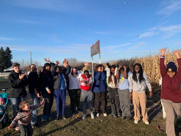 Group of people joyfully tossing leaves in the air on a sunny day.