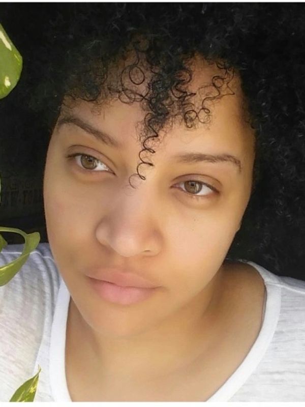 Close-up of a woman with curly hair and a thoughtful expression.