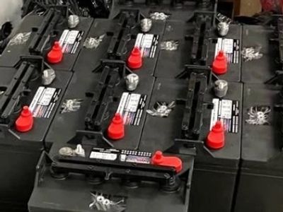 A group of black car batteries with red and black terminals arranged together.