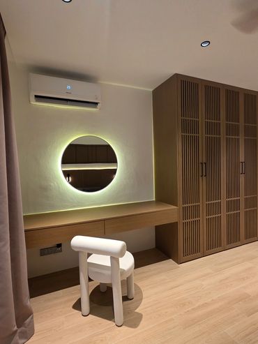 Minimalist vanity area with round backlit mirror and unique white chair.