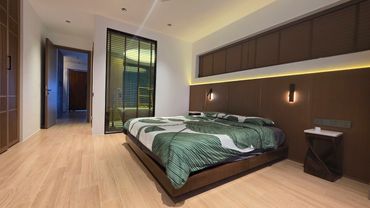 Modern bedroom with wooden flooring and green patterned bedding.