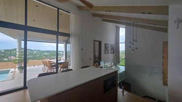 Modern kitchen island with panoramic view and outdoor dining area.