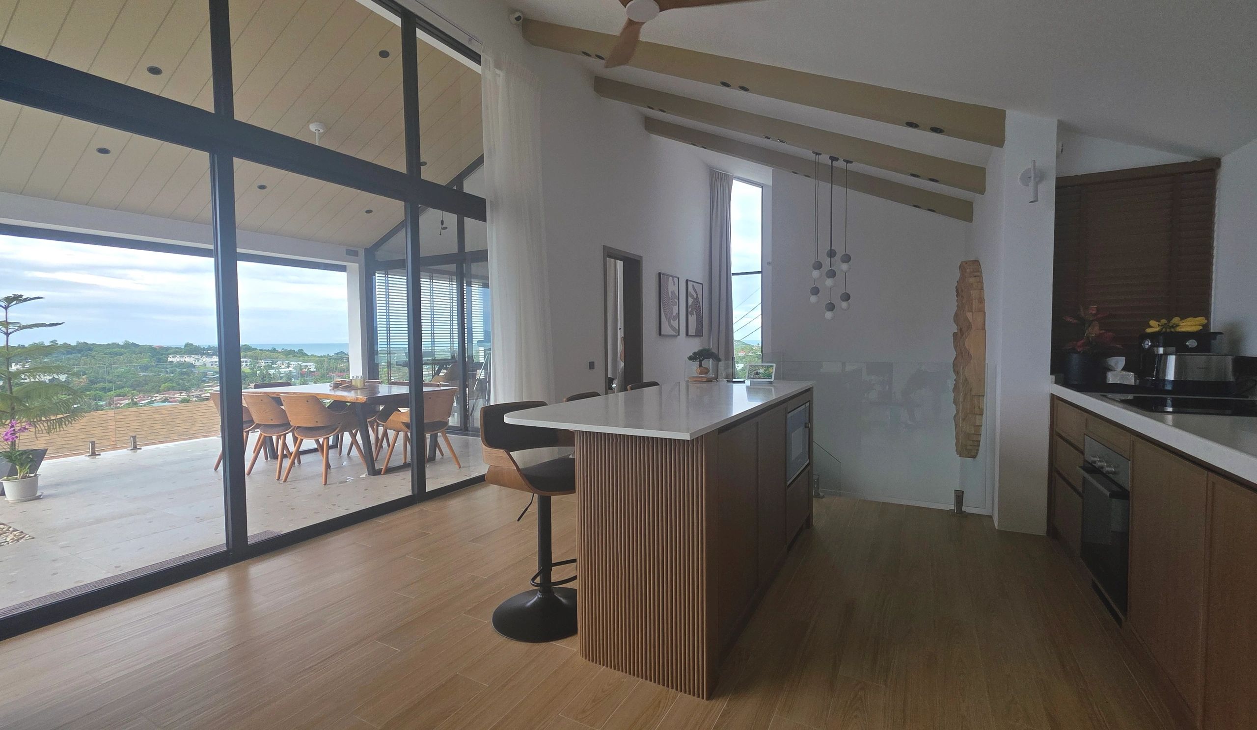 Modern kitchen with island and outdoor dining area overlooking a scenic view.