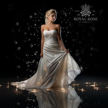 Elegant woman in a glowing white gown against a dark, sparkling backdrop.
