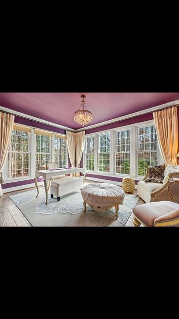 Elegant sitting room with purple walls, large windows, and classic furniture.