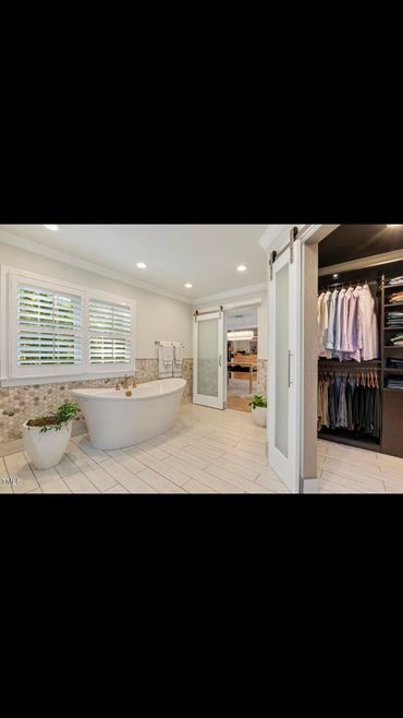Modern bathroom with a freestanding tub and sliding doors leading to a walk-in closet.