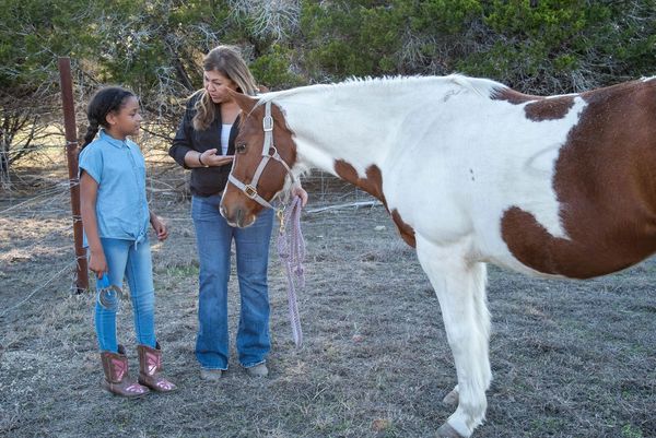 Girl receives lesson about horse care during equine-assisted learning session