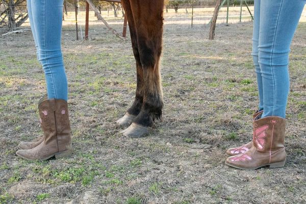 Cowboy boots alongside horse hoofs