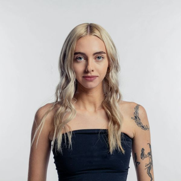 Blonde woman with tattoos wearing a black strapless top.