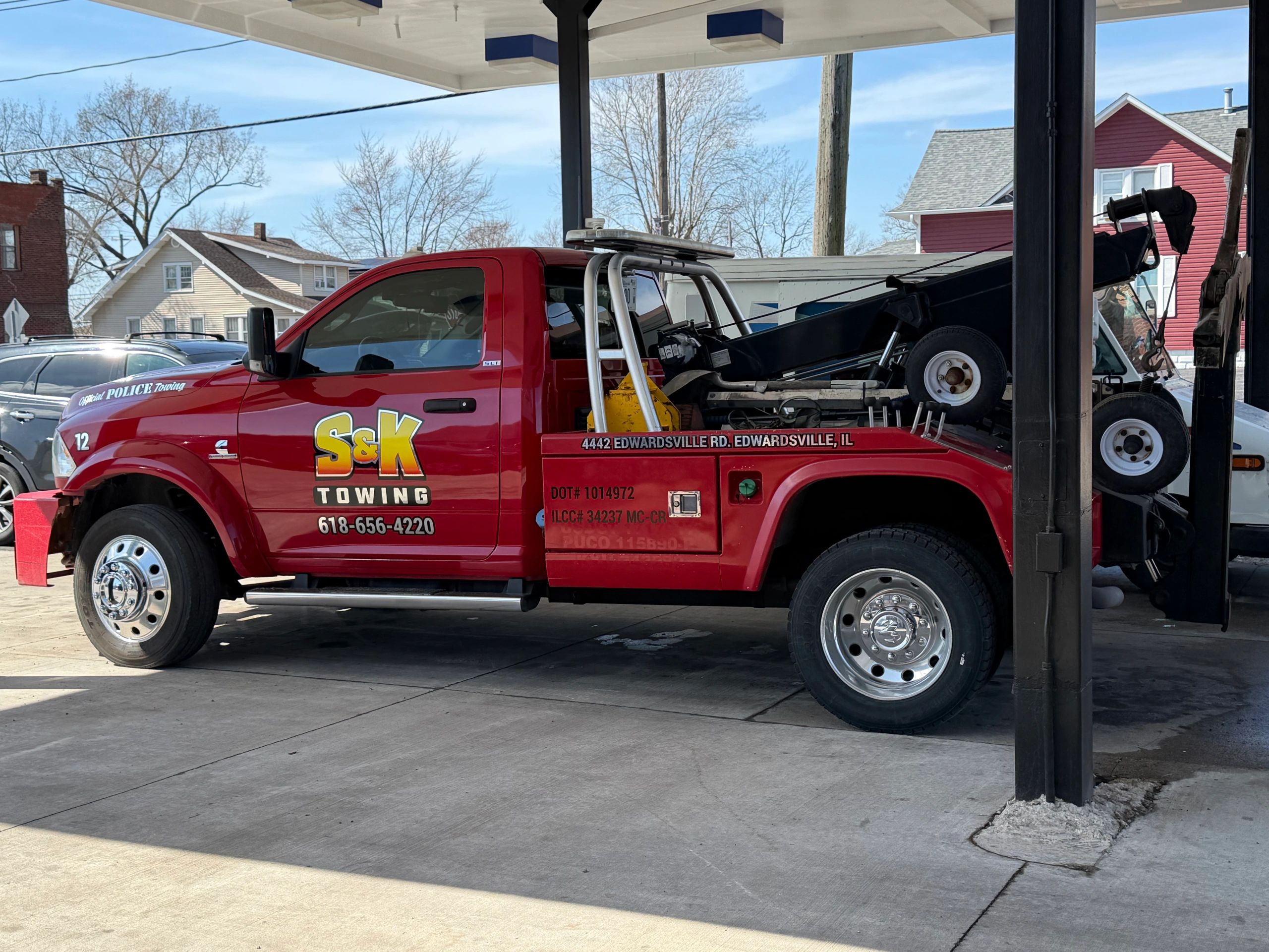 Red S&K Towing truck parked at a gas station on a sunny day.