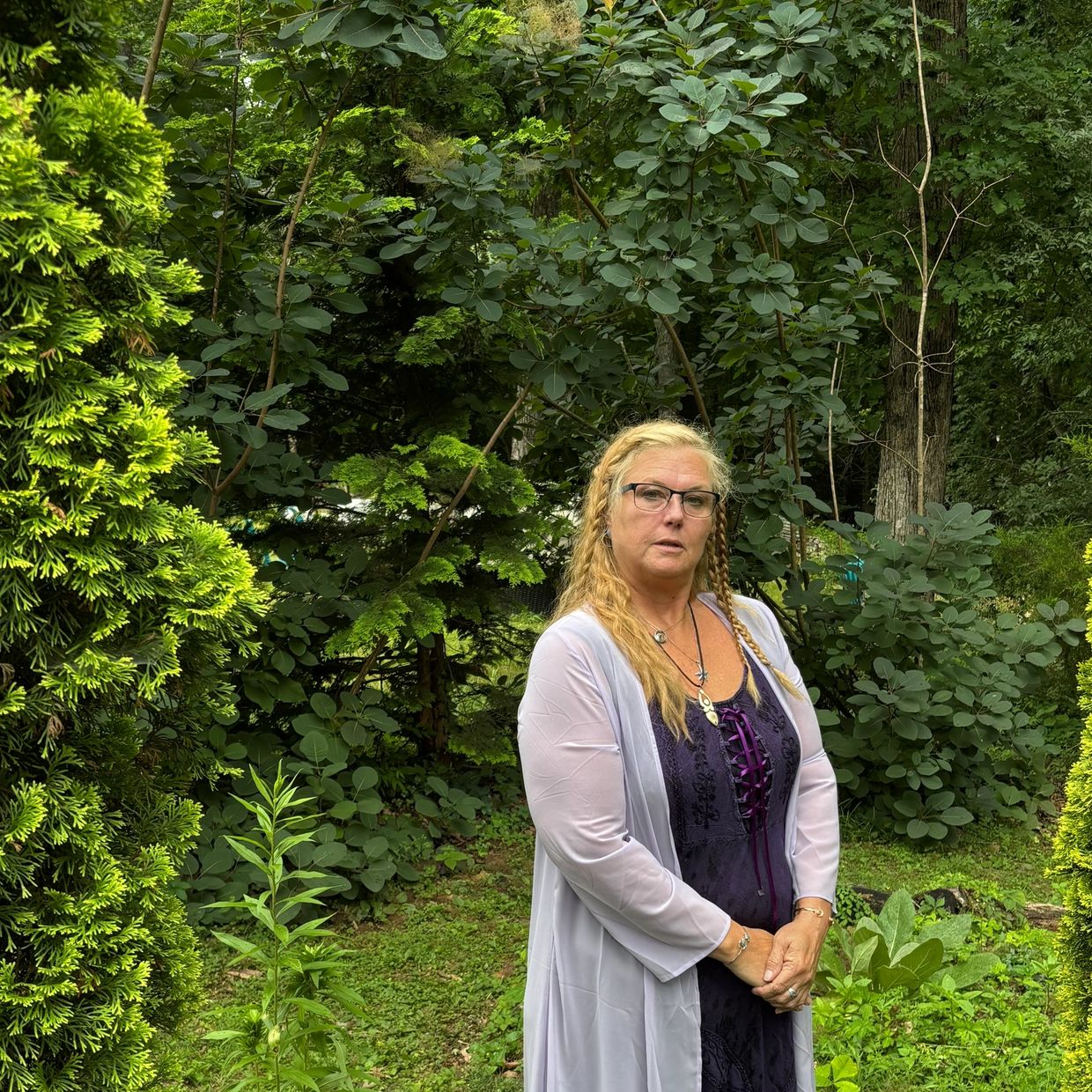 Woman posing in a lush green garden.