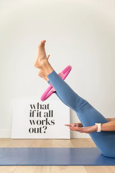 Person exercising with a pink Pilates ring and motivational quote in background.
