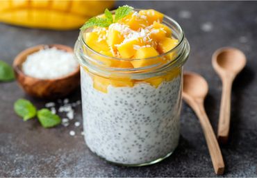 Chia pudding topped with fresh mango and shredded coconut in a glass jar.