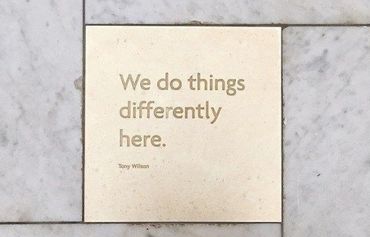Stone tile with the quote "We do things differently here." by Tony Wilson.