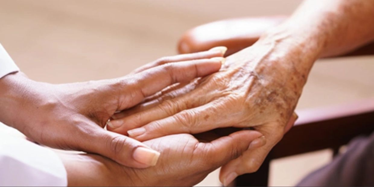 Black Caregiver holds hands with client