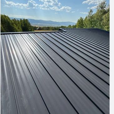 Newly installed sleek black metal roof under a blue sky.