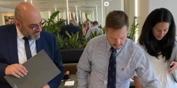 Three professionals reviewing documents in an office setting with mirrors and plants.