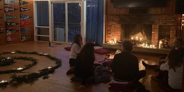 People sitting in a cozy room around a candlelit fireplace.