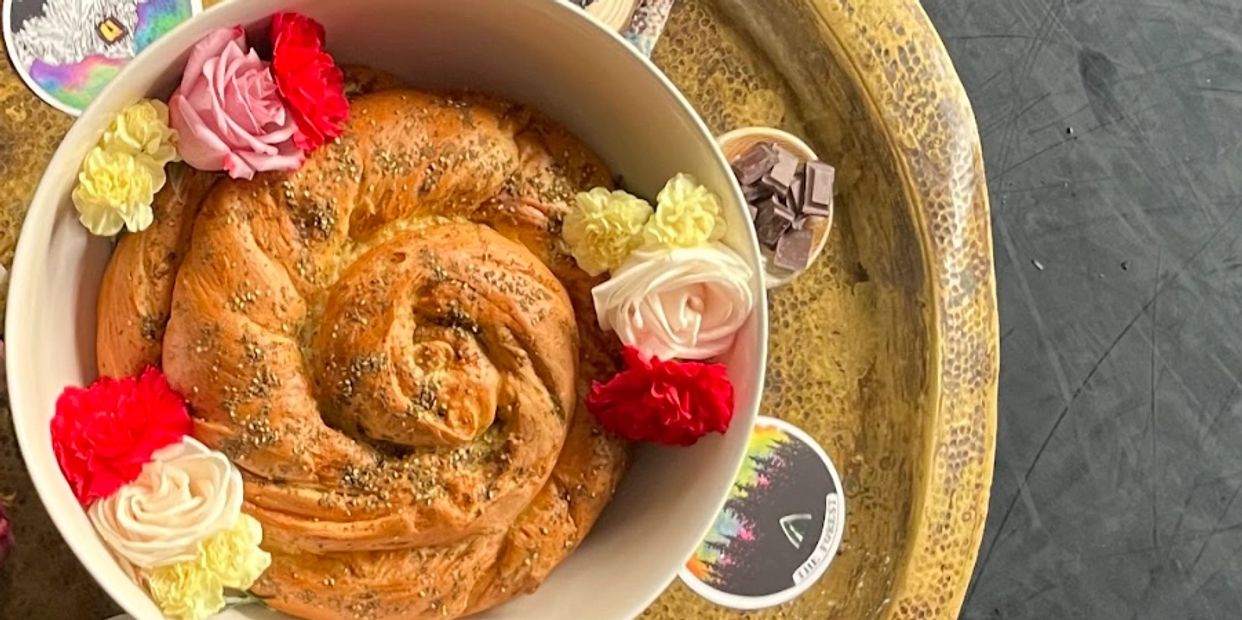 A spiral bread garnished with colorful flowers in a bowl.