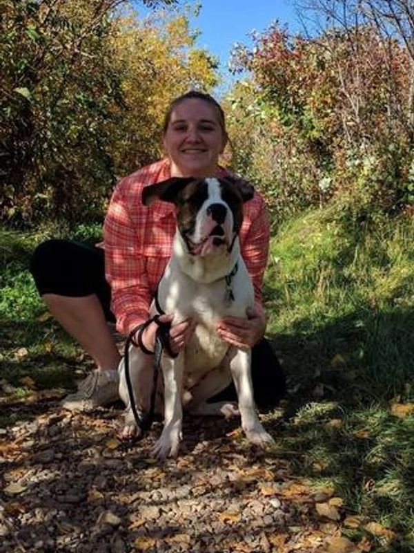 Auntie Jacklyn with her large brown and white dog. Outdoor, with trees and grass behind