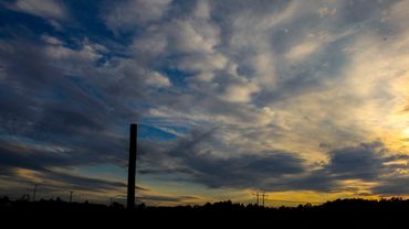 Dramatic sunset sky with silhouetted landscape and utility poles.