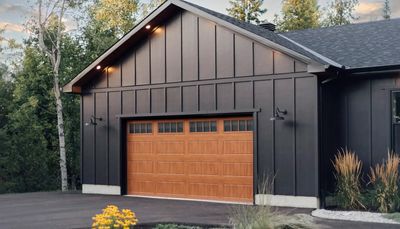 Modern garage with black exterior and wooden door.