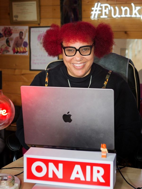 michelle sat at a desk behind an open laptop with an on air sign in front of laptop