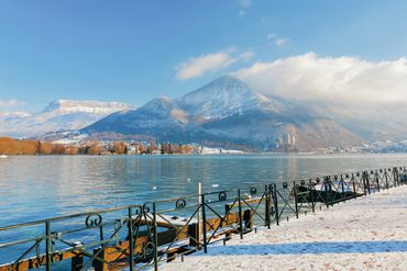 Snow-covered mountains and a serene lake under a clear blue sky.