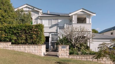 White two-story house with a front garden and a stone wall.