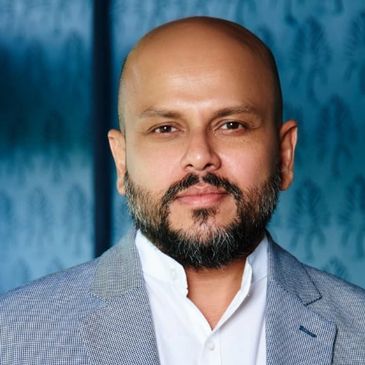 Portrait of a confident bald man with a beard in a gray blazer.