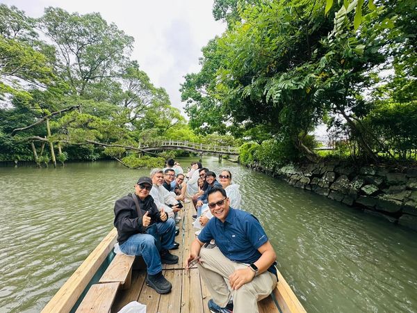 Group of people enjoying a boat ride on a lush green river.