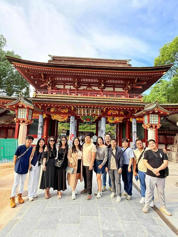 Group photo of friends in front of a traditional Japanese temple gate.