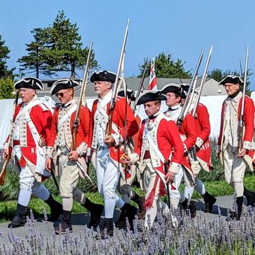 British redcoats march by colonial camps.