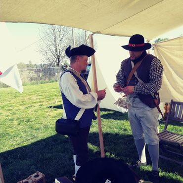 Two colonial soldiers talk to each other in camp.