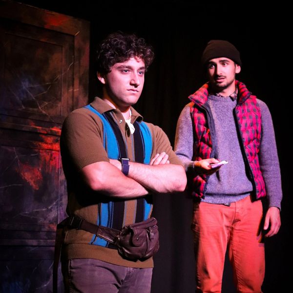 Two men in a dramatic scene, one serious, one holding a note.
