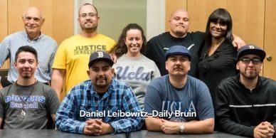 Group photo of nine diverse people smiling indoors.