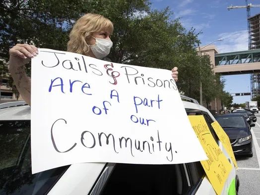 Woman holding a protest sign about jails and prisons.