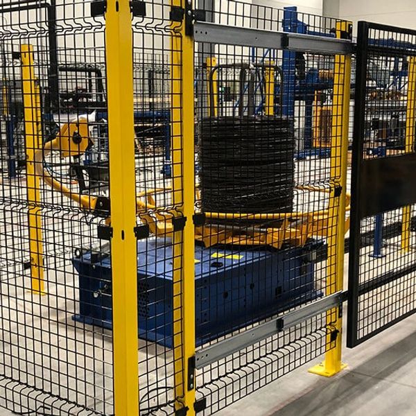 Industrial robotic arm inside a yellow safety cage in a factory setting.