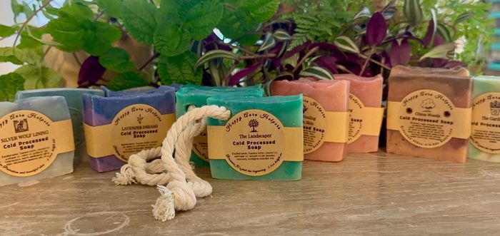 Colorful handmade soaps with natural labels and a rope, placed on a wooden surface.
